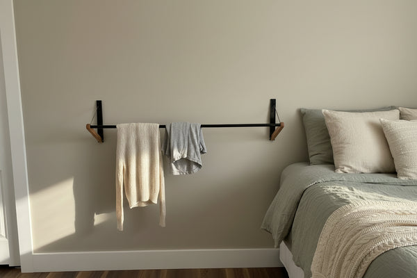 Foldable FOLD.ONE rack mounted on bedroom wall holding sweaters, demonstrating easy access and efficient storage