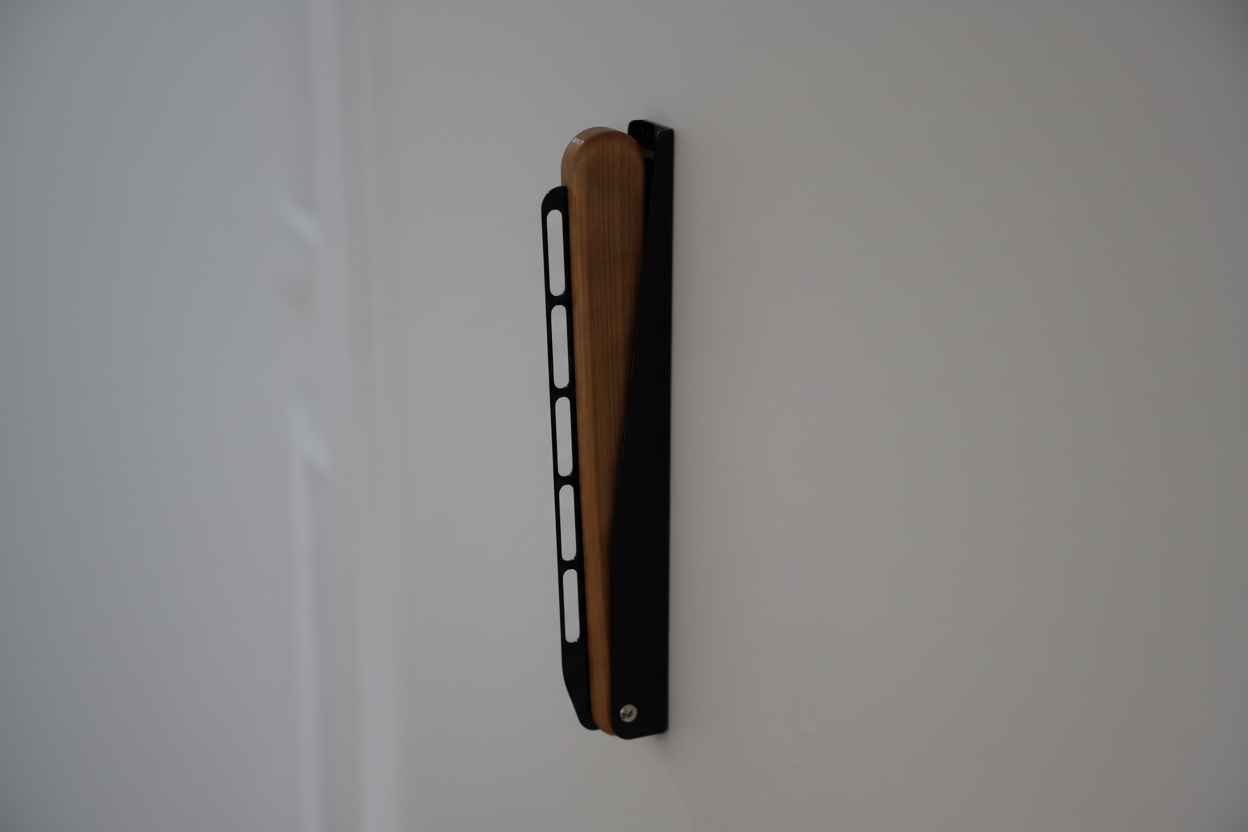 Foldable wall-mounted garment rail folded flat when not in use.