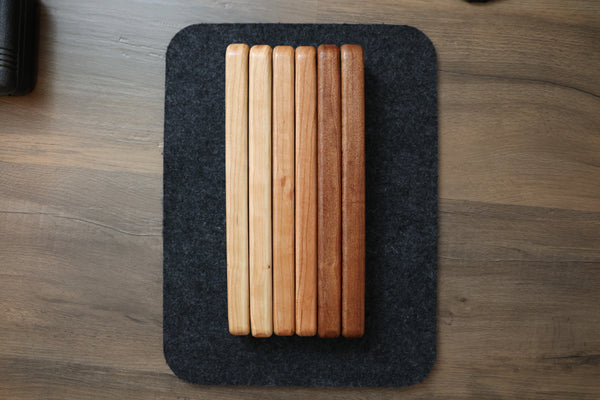 Close-up of FOLD.ONE wood lever finishes showing grain texture in cherry light, cherry regular and sapele (from left to right)