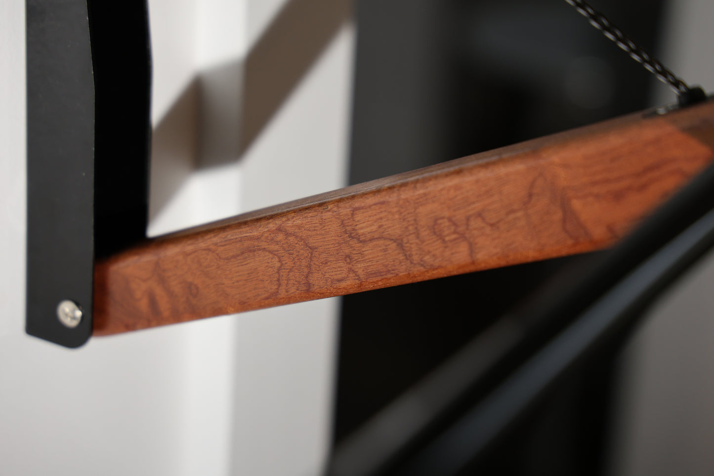 Detail of lacquered wood lever on FOLD.ONE rack in studio setting (Color: Wood Lover (Sapele))